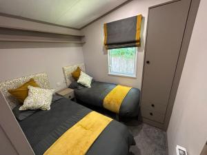 a small bedroom with two beds and a window at Luxury Hot Tub Lodge 5 Star Country Park Huge Veranda Colour Change Hot Tub Private Fishing FREE Parking in Malton