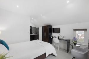 a white bedroom with a bed and a chair at Modern city centre studio apartment! in Oxford