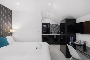 a bedroom with a white bed and a kitchen at Modern city centre studio apartment! in Oxford