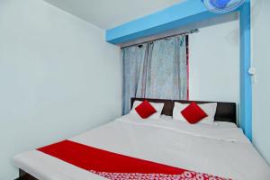 łóżko z białymi i czerwonymi poduszkami w pokoju w obiekcie OYO Flagship Shillong Homestay w mieście Shillong