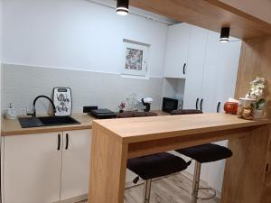 a kitchen with white cabinets and a wooden counter top at Central Train Station Apartment in Braşov