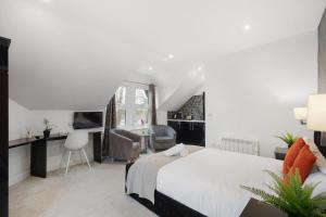 a bedroom with a large white bed and a desk at Modern city centre studio apartment in Oxford