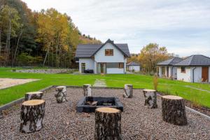 ein Haus mit einem Garten mit Holzscheiten und einer Feuerstelle in der Unterkunft Domki Kamieniec 