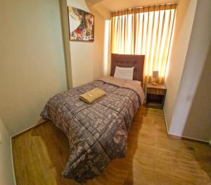 una camera da letto con un letto con una coperta e una finestra di Fiflo's Apartament II a Cuzco