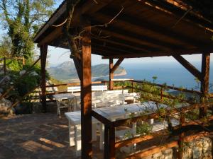 a wooden pavilion with tables and a view of the ocean at Adriatrek Bed & Breakfast in Petrovac na Moru