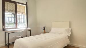 1 dormitorio con cama, escritorio y ventana en Casa en Los Remedios en Sevilla