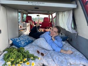 Uma mulher deitada numa cama numa carrinha. em Rent a Blue Classics' s Campervan for your Road trip in Portimao -VOLKSWAGEN T3 em Portimão