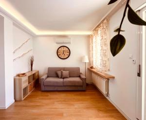 a living room with a couch and a clock on the wall at IL DANDY appartamento con parcheggio in Trieste