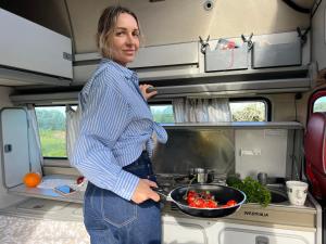 Uma mulher numa caravana com uma tigela de comida. em Rent a Blue Classics' s Campervan for your Road trip in Portimao -VOLKSWAGEN T3 em Portimão