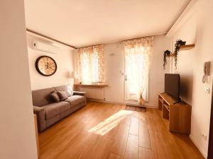 a living room with a couch and a clock on the wall at IL DANDY appartamento con parcheggio in Trieste