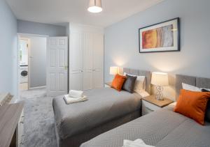 a bedroom with two beds with orange pillows at Crawley Thornhill 1 Bed Apartment near Gatwick Airport with Free Parking in Ifield