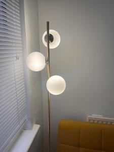 a lamp with three lights in a room with a couch at De Luxe apartment 1 in Leicester