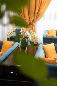 una sala de estar con sofás azules y un jarrón con flores en Melas Hotel, en Merate