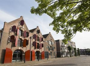 een oud bakstenen gebouw met rode en witte ramen bij Hotel Restaurant Talens Coevorden in Coevorden