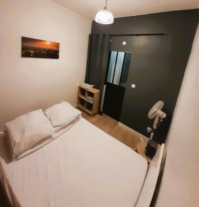 Dormitorio pequeño con cama blanca y lámpara en L'industirel Narbonnais, en Narbona