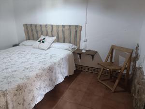 1 dormitorio con cama y silla de madera en Finca del Abu, en Los Marines