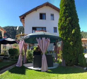 a couple sitting under an umbrella in front of a house at Guest House Niya in Beli Iskar