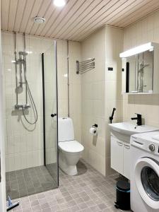 a bathroom with a shower and a toilet and a sink at Kotimaailma Apartments Tervapääsky I in Oulu