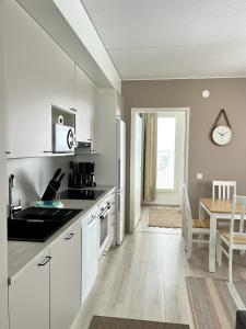 a kitchen with white cabinets and a table with a dining room at Kotimaailma Apartments Tervapääsky I in Oulu