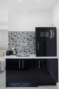 a kitchen with a sink and a black refrigerator at Modern city centre studio apartment 202 in Oxford