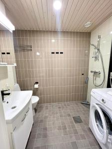 a bathroom with a washing machine and a sink at Kotimaailma Apartments Tervapääsky I in Oulu