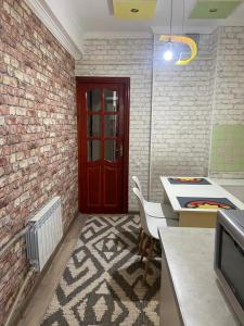 uma cozinha com uma porta vermelha e uma mesa e cadeiras em Апартаменты em Shymkent