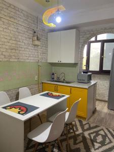 uma cozinha com uma mesa e cadeiras e um lavatório em Апартаменты em Shymkent