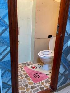 uma casa de banho com um WC e um tapete rosa em Апартаменты em Shymkent