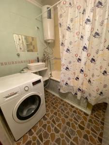 uma casa de banho com uma máquina de lavar roupa e uma cortina de chuveiro em Апартаменты em Shymkent