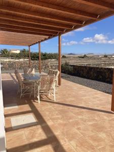eine Terrasse mit einem Tisch und Stühlen unter einem Dach in der Unterkunft Rosa de la laguna in Lajares