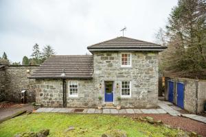uma casa de pedra com uma porta azul num quintal em Gardeners Cottage em Challoch