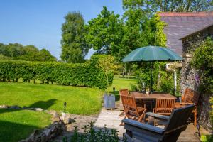 a patio with a table and chairs with an umbrella at Glenydd Rhydlewis in Rhyd Lewis