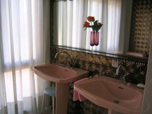 uma casa de banho com dois lavatórios e um vaso de flores na parede em Casa Vintage delante del mar para 15 huéspedes em San Vicente de Calders