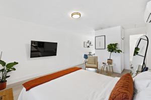 a white bedroom with a bed and a tv on the wall at Lovely Rental Unit with free Parking on Premises in Fort Lauderdale