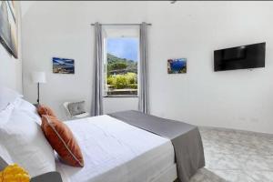 a white bedroom with a bed and a window at Sorrento Realty Holidays Nagy House in Sant'Agnello