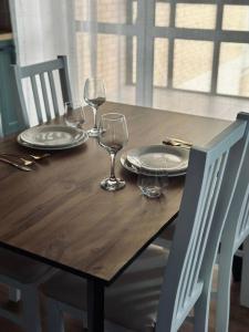 a wooden table with plates and wine glasses on it at Элитные современные апартаменты с гостиничным сервисом in Karagandy