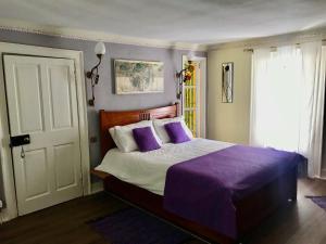 a bedroom with a bed with purple sheets and a window at Organic Welltree in Saint Martins