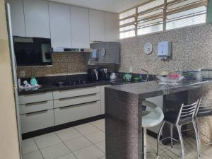 uma cozinha com armários brancos e um balcão com cadeiras em Lindo Sobrado Bandeirantes 4 quartos em Ribeirão Preto
