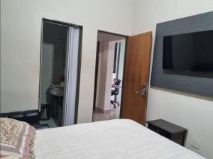 a bedroom with a bed and a flat screen tv at Lindo Sobrado Bandeirantes 4 quartos in Ribeirão Preto