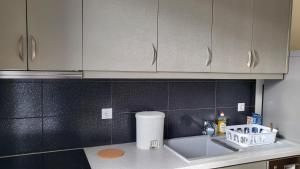 a kitchen counter with a sink and white cabinets at Eirini Home in Andros