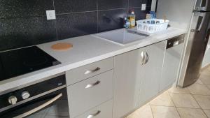 a white kitchen with a sink and a stove at Eirini Home in Andros