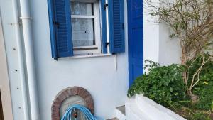 a house with a blue window and a blue bench at Eirini Home in Andros