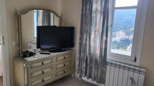 a television on top of a dresser with a window at Eirini Home in Andros