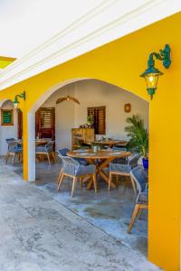 a patio with a yellow wall and wooden tables and chairs at Boutique Hotel Wanapa in Kralendijk