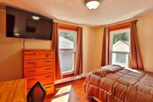 a bedroom with a bed and a dresser with a television at The Hill All Star Baseball Rentals in Oneonta