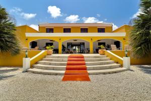 a yellow house with a red carpet on the stairs at Boutique Hotel Wanapa in Kralendijk