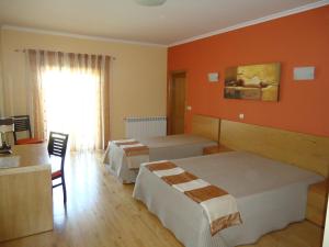 a hotel room with two beds and a desk at Hotel Encostas De Nantes in Chaves