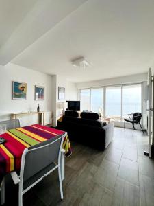 ein Wohnzimmer mit einem Sofa und einem Tisch in der Unterkunft Mirasables - Appartement dernier étage terrasse vue mer in Les Sables-dʼOlonne