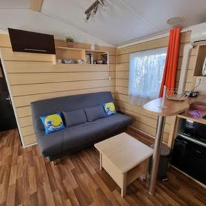 een kleine woonkamer met een bank en een tafel bij Mobile Home cosy 4/6 pers in Hyères