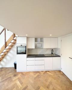 een open keuken met witte kasten en houten vloeren bij Mayfair Suites in Antwerpen